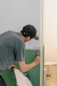 A man painting walls with a roller during home renovation indoors.